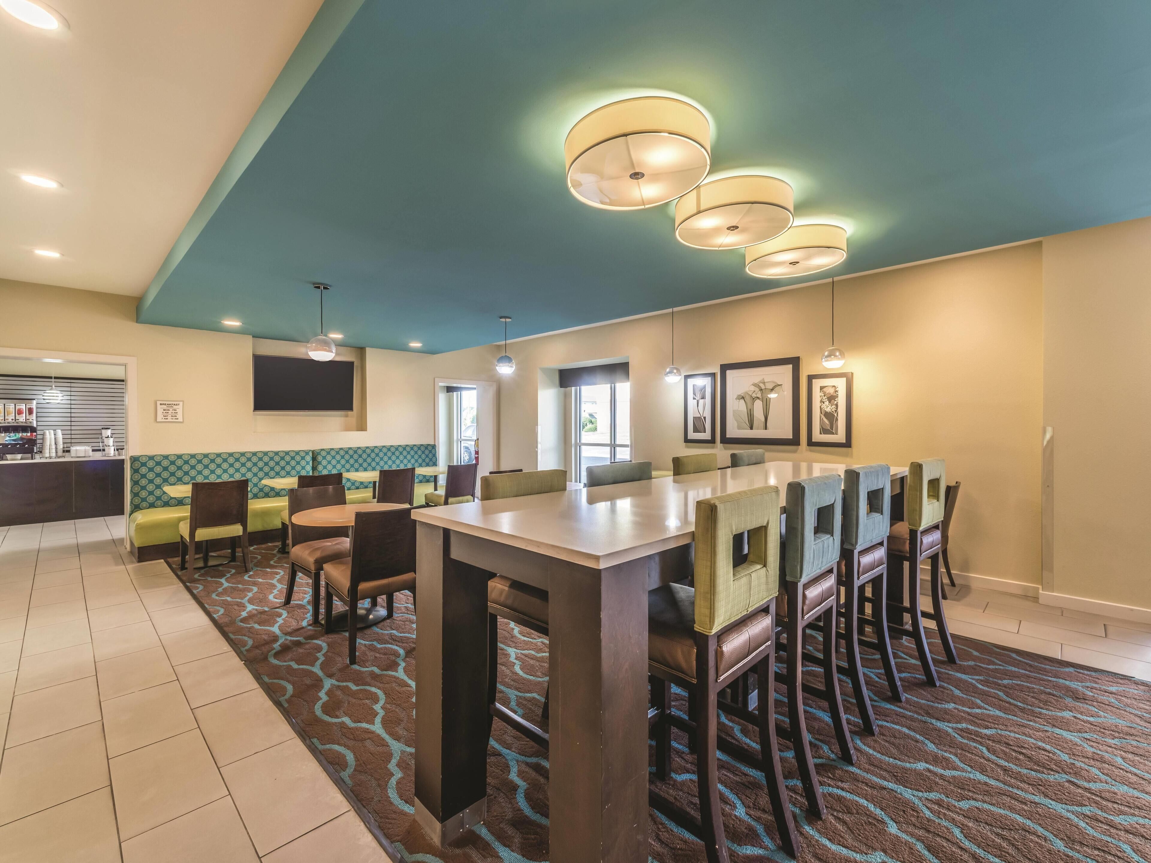 A dining area with a long table, chairs, and a patterned carpet.
