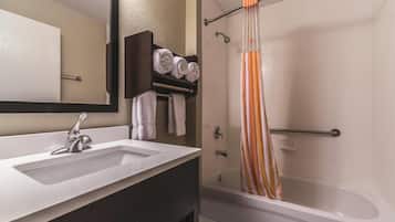Un baño moderno con un lavabo blanco, tocador oscuro y una ducha con cortina a rayas.