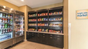 A vending area with a refrigerator and shelves stocked with snacks and drinks. - La Quinta Inn & Suites by Wyndham Collinsville - St. Louis (Collinsville)