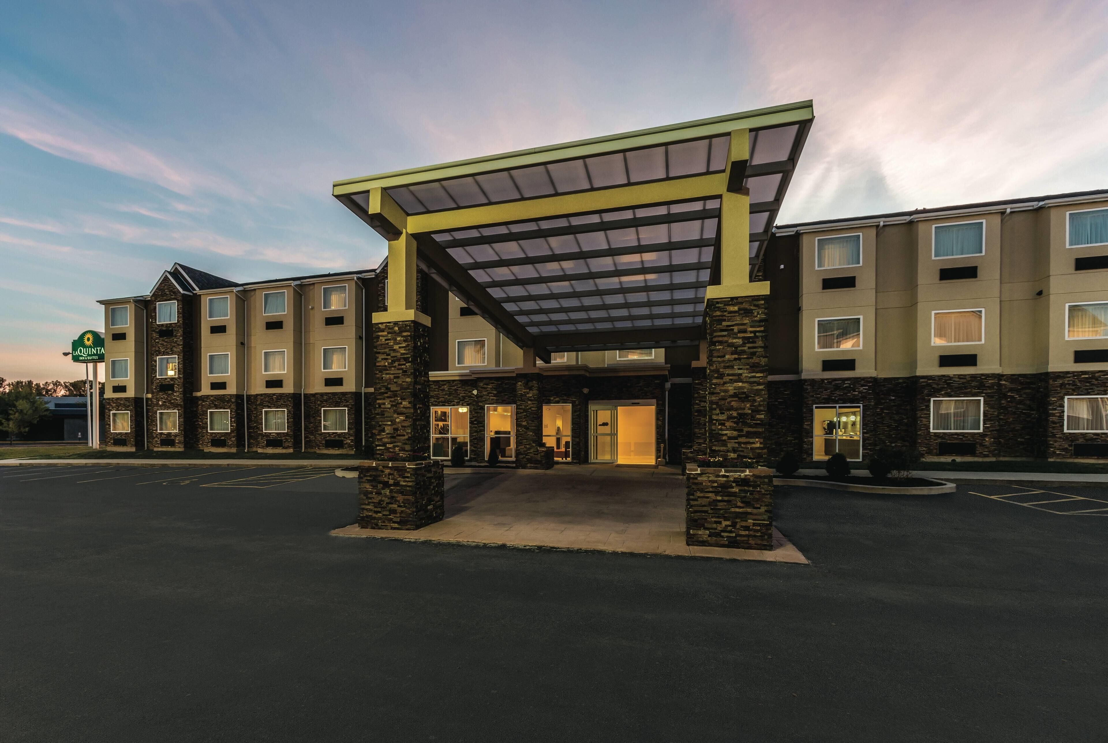A hotel with a covered entrance, multiple floors, and a parking lot.