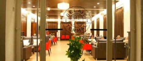 Vestíbulo de hotel con mostrador de recepción, zona de estar y una planta en maceta.