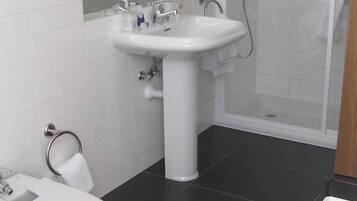Un baño con inodoro, lavamanos y ducha.