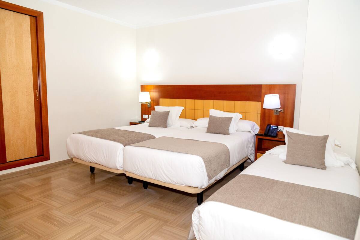 Une chambre d’hôtel avec deux lits, des têtes de lit en bois, des lampes de chevet et un plancher en bois.