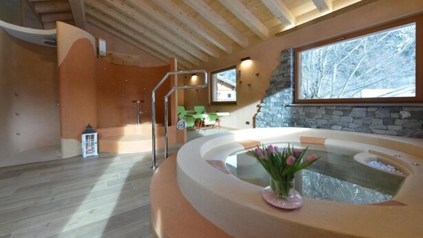 Un interior moderno con pared de piedra, un ventanal grande y un jacuzzi.