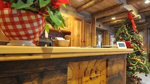 Un mostrador de recepción de madera con un panel tallado, un árbol de Navidad y plantas de poinsettia.