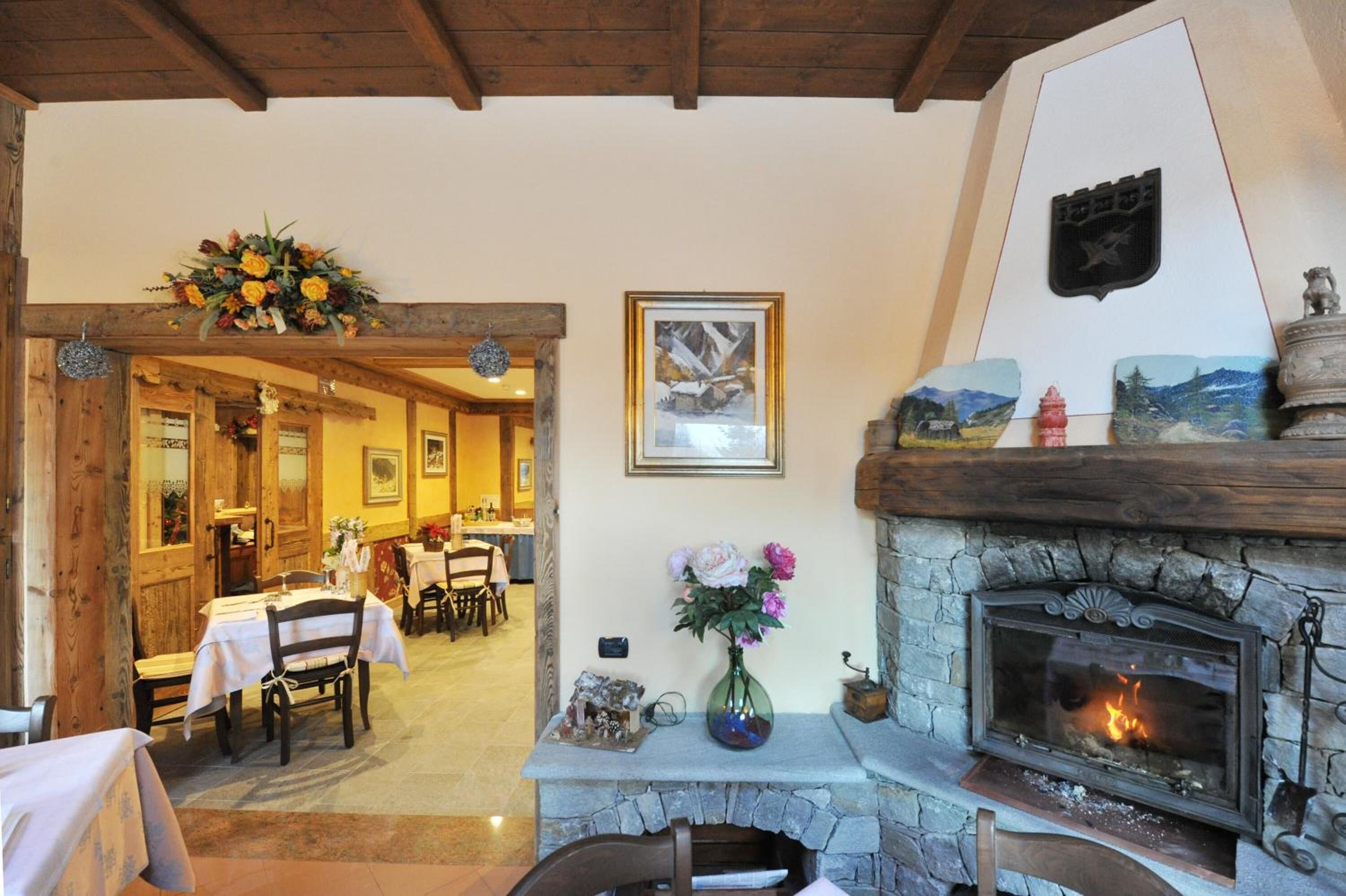 A dining area with wooden tables and chairs, a fireplace with a stone surround, and a wall-mounted emblem.