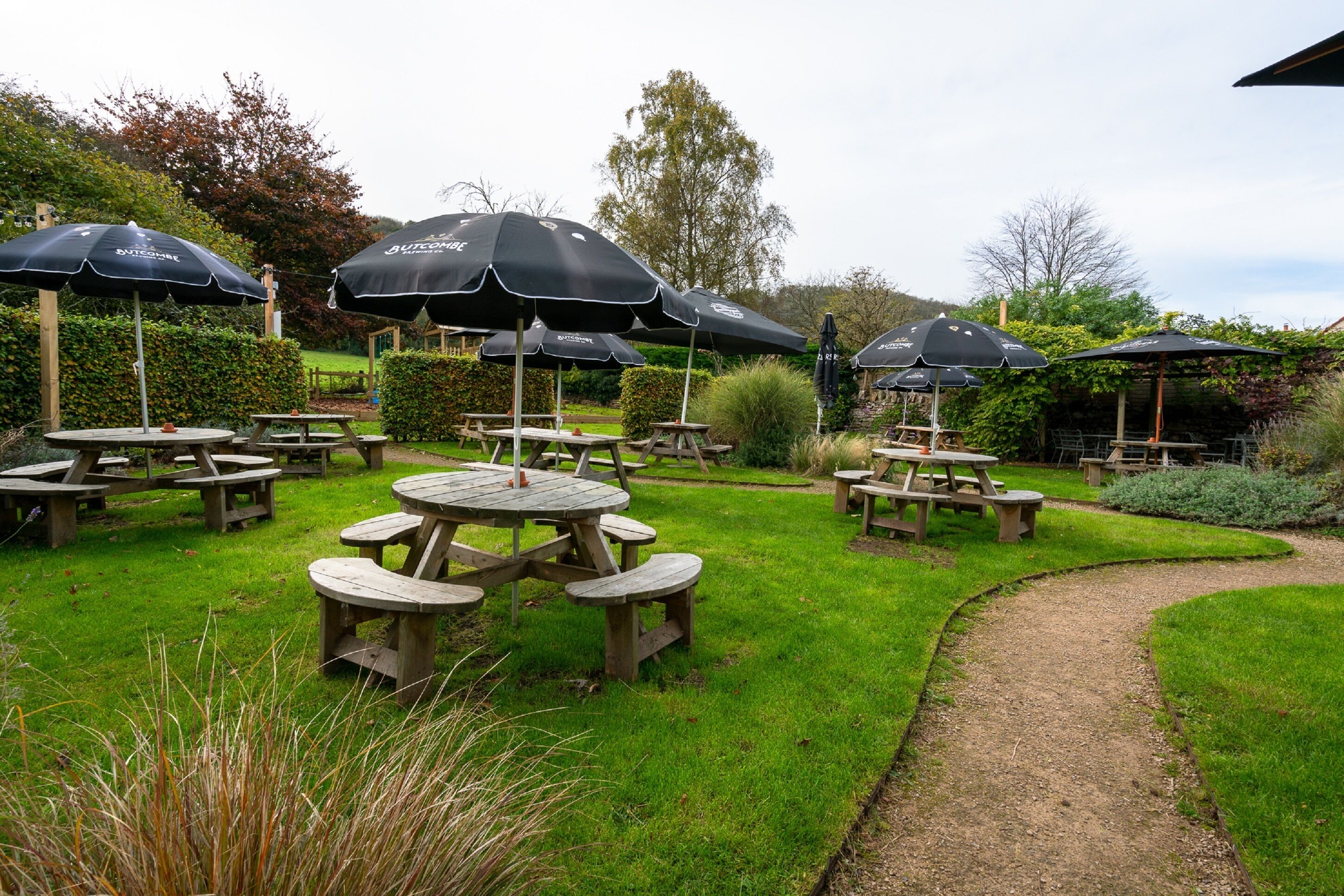 An outdoor patio area with multiple picnic tables and black umbrellas.