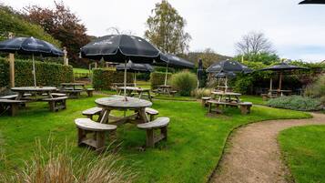An outdoor patio area with multiple picnic tables and black umbrellas.