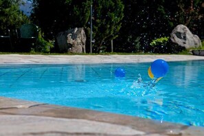 A swimming pool with clear water and a blue and yellow ball in motion. - FamilyHotel Stegerhaus (Valle Aurina)