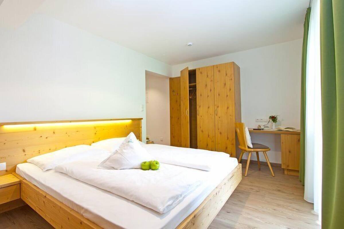A bedroom with a wooden bed, a desk, and a wardrobe.