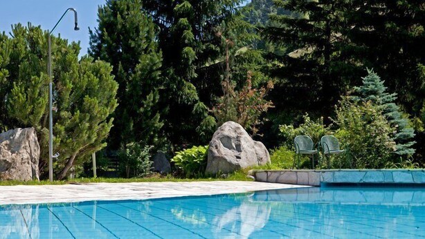 Ein Schwimmbecken mit klarem, blauem Wasser, umgeben von Felsen und Grünpflanzen.