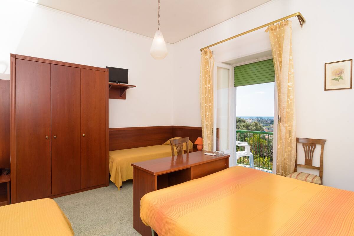 Ein Schlafzimmer mit zwei Betten, einem Holzschrank, einem Schreibtisch und einem Stuhl.