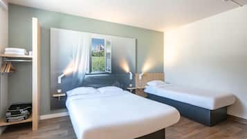 Une chambre moderne avec deux lits, une armoire et une vue sur un paysage montagneux par la fenêtre.
