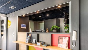 Un mostrador de recepción con una computadora, una planta y un teléfono.