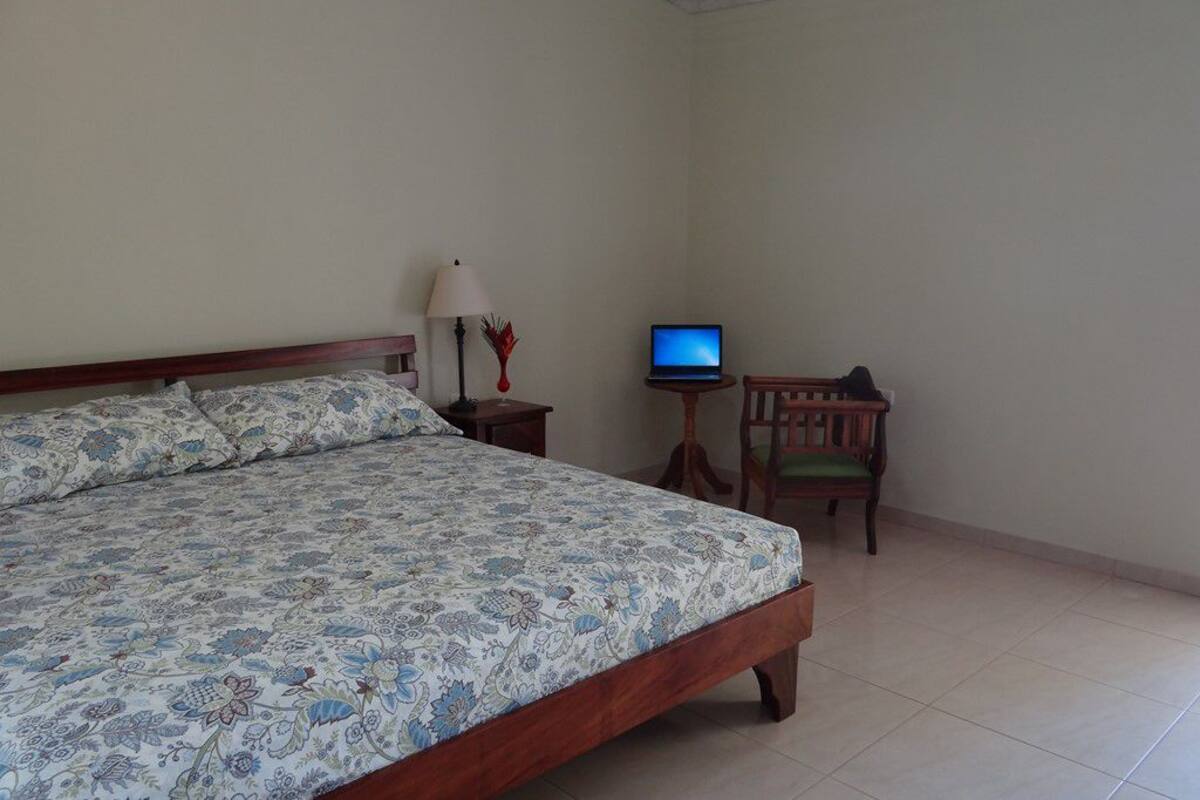 Un dormitorio con una cama, un escritorio con computadora, una lámpara y una silla.