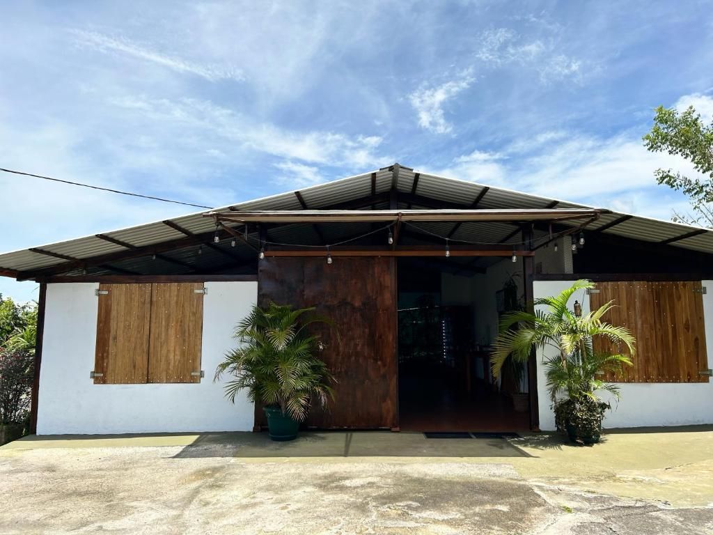 Un edificio con techo metálico, contraventanas de madera y entrada de concreto.