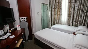 Habitació d'hotel amb dos llits, una taula de treball amb cadira, televisió i zona de banyera amb dutxa.