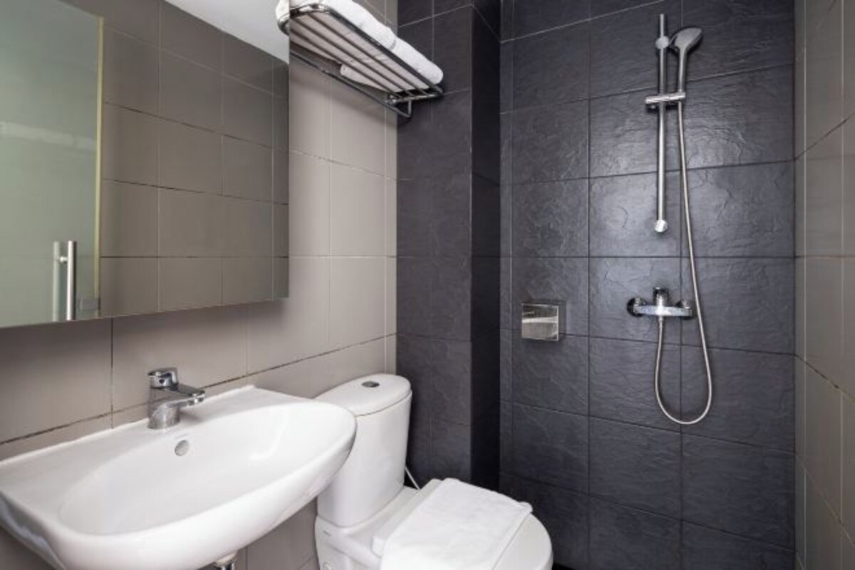 Een moderne badkamer met een wit wastafel, toilet en douche met handdouche.