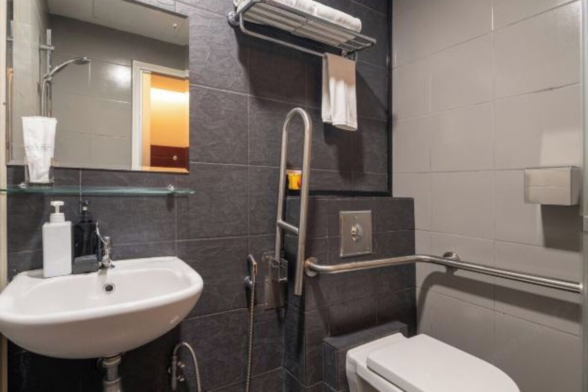 Een moderne badkamer met een wit wastafelmeubel, een douchecabine van glas, een toilet en een handdoekrek.