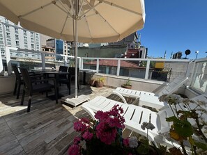 A rooftop terrace with a table and chairs, a lounge area with white chairs, and potted plants. - Ten Rooms Hotel Istanbul  (Istanbul)