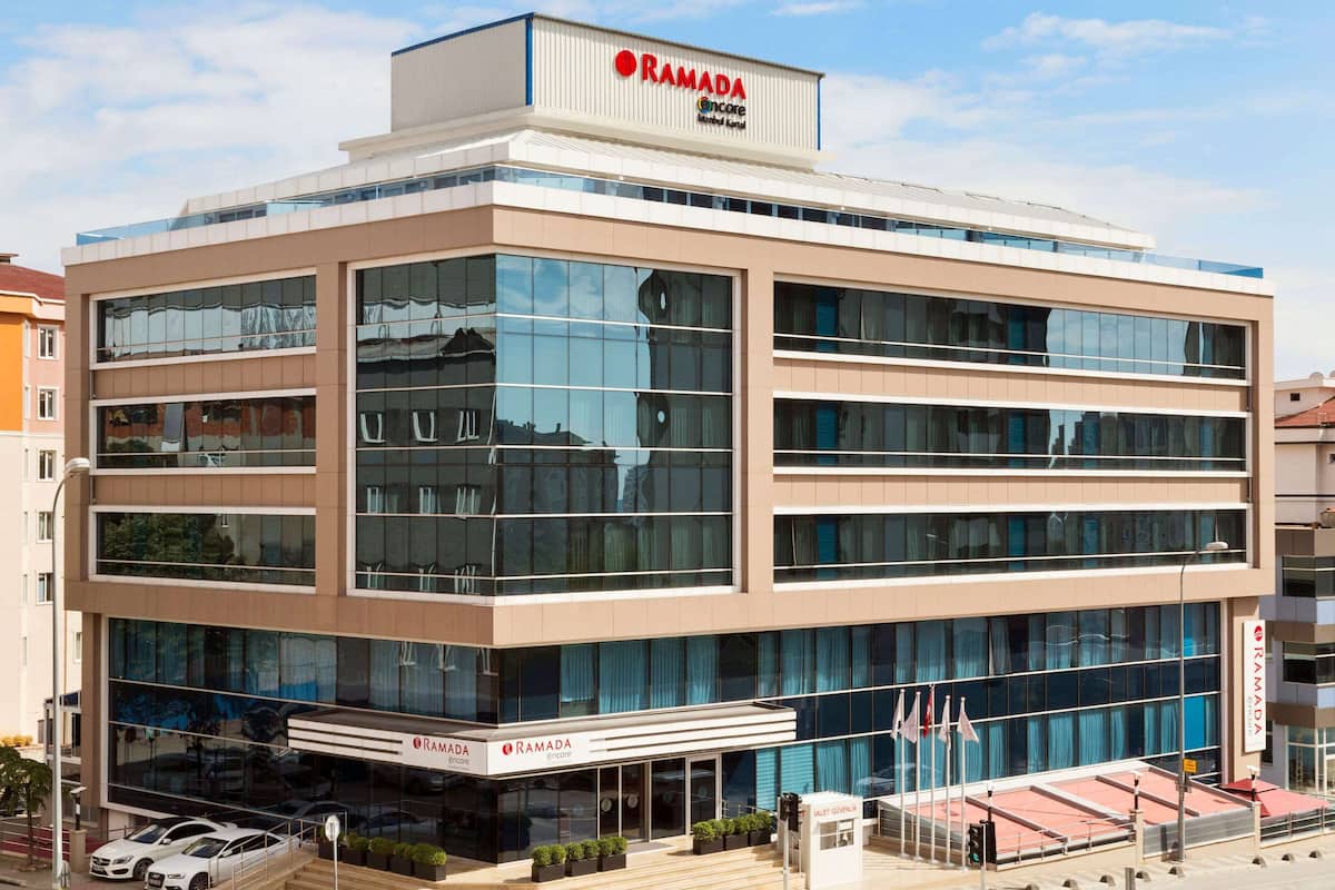 A multi-story building with a modern design, featuring large glass windows and a prominent 'RAMADA' sign at the top.