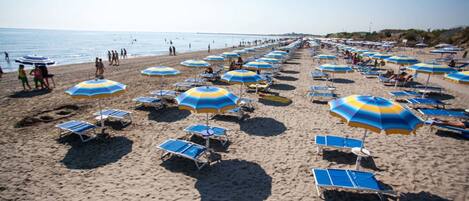 A beach with rows of sunbeds and umbrellas.