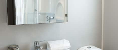 Un baño con un lavamanos blanco, un espejo, un inodoro y un armario.