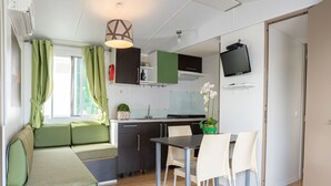 A compact kitchenette with a sink, stove, and a flat-screen TV mounted on the wall. - Campingvillaggio Atlanta e Mediterraneo - Campground (Chioggia)