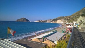 Vista costera con playa, sombrillas y una bandera.