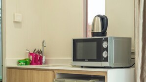 Una kitchenette compacta con microondas, un refrigerador pequeño y un lavamanos.