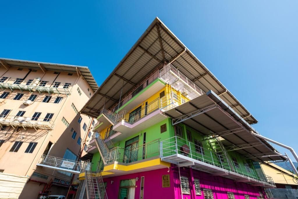 A multi-story building with a green and yellow facade, multiple balconies, and a visible reception area.