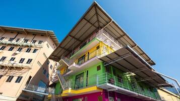 A multi-story building with a green and yellow facade, multiple balconies, and a visible reception area.