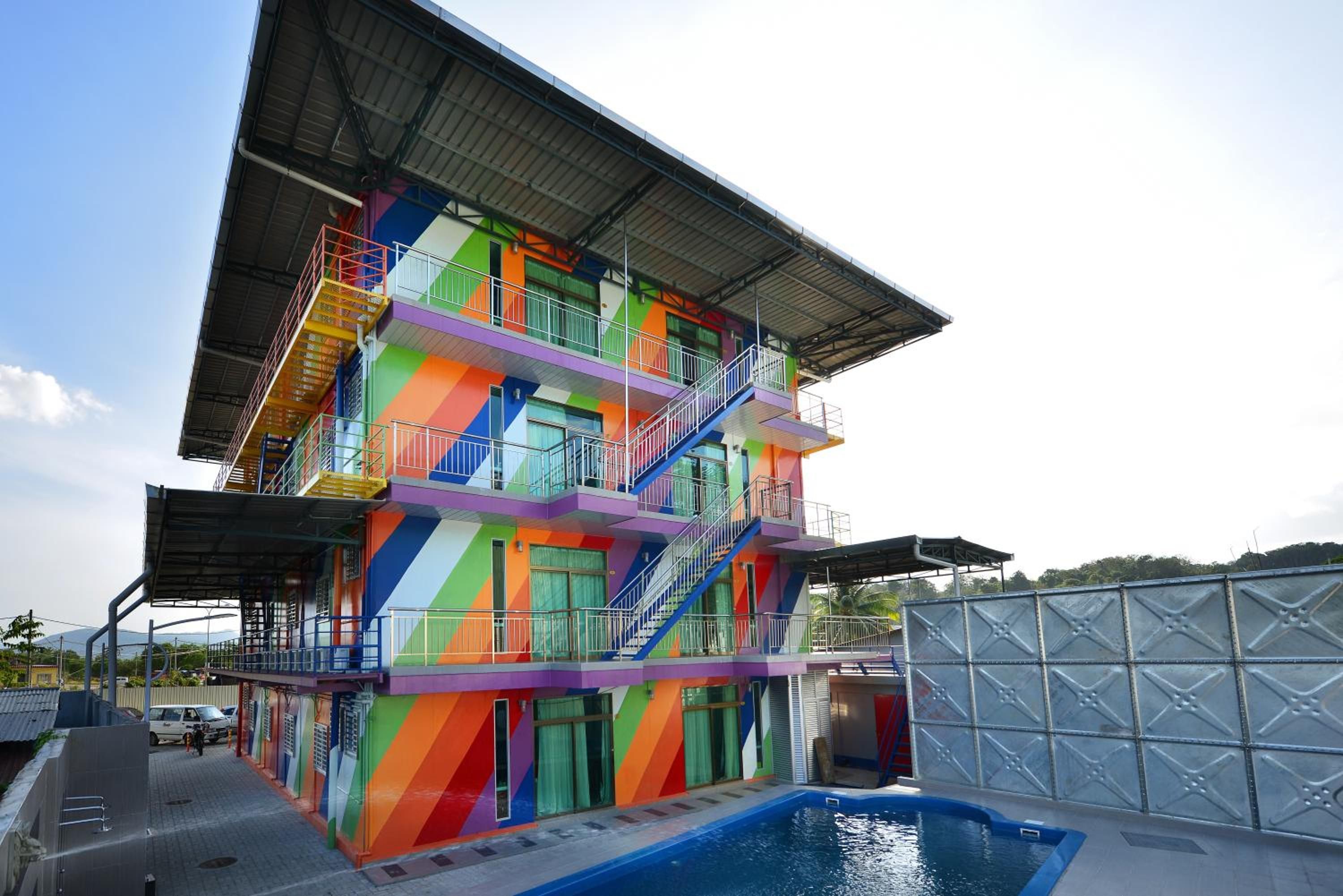 Un edificio de varios pisos con fachada colorida, piscina y una zona cubierta.