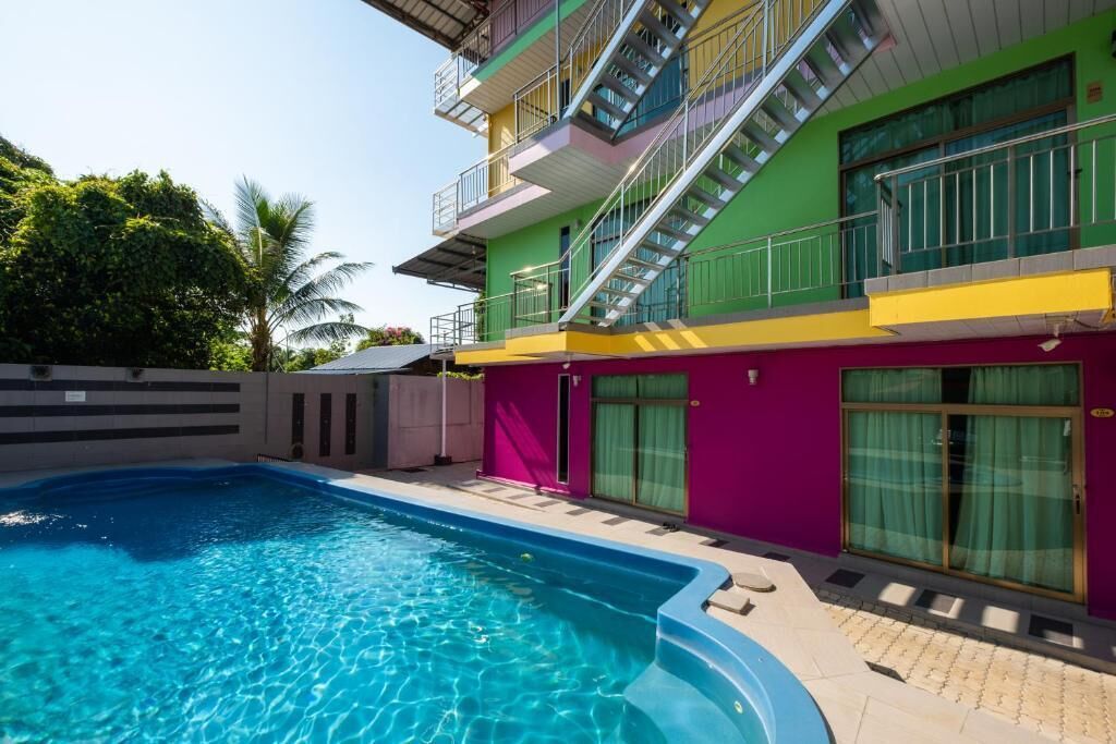 A swimming pool adjacent to a multi-story building with balconies and large windows.