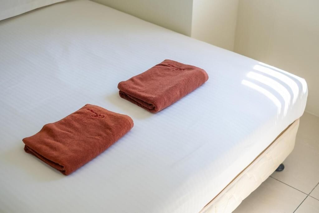 A bed with a white mattress and two folded towels.