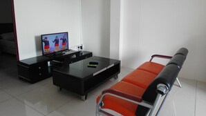 Una sala de estar moderna con un televisor de pantalla plana, un mueble de entretenimiento negro y un sofá rojo y negro.