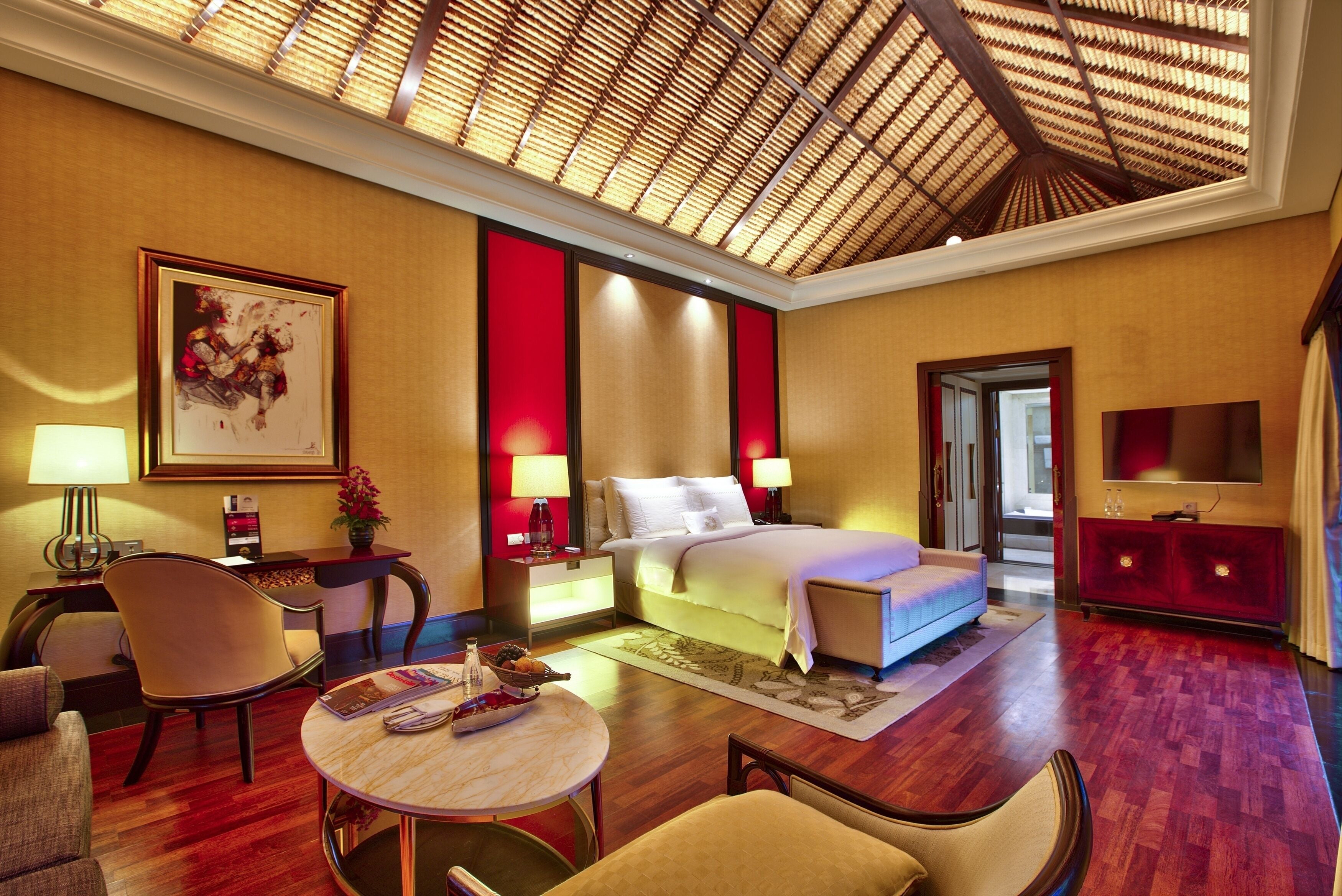A hotel room with a bed, a desk, a chair, a round table, and a TV.