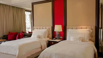Een hotelkamer met twee bedden, een rode accentmuur en een raam met gordijnen.