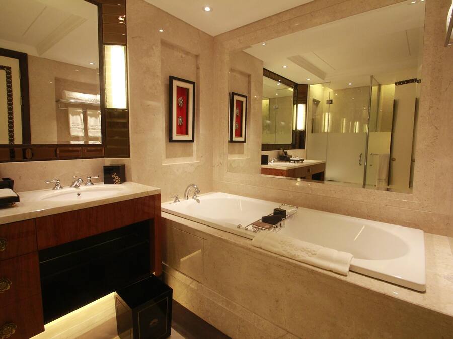 A modern bathroom with two sinks, a large bathtub, and a walk-in shower.
