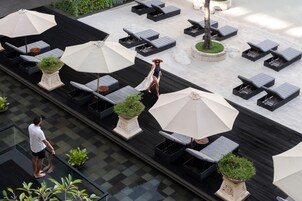 Un espace de détente extérieur doté de différents types de sièges, notamment des fauteuils et des tables, dont certains sont équipés de parasols.