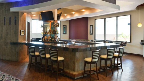 Un área de bar moderna con una isla central, taburetes y una barra bien surtida.