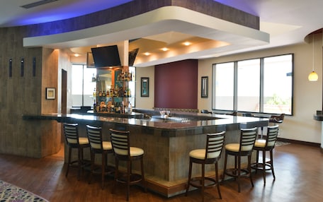 A modern bar area with a central island, bar stools, and a well-stocked bar counter.