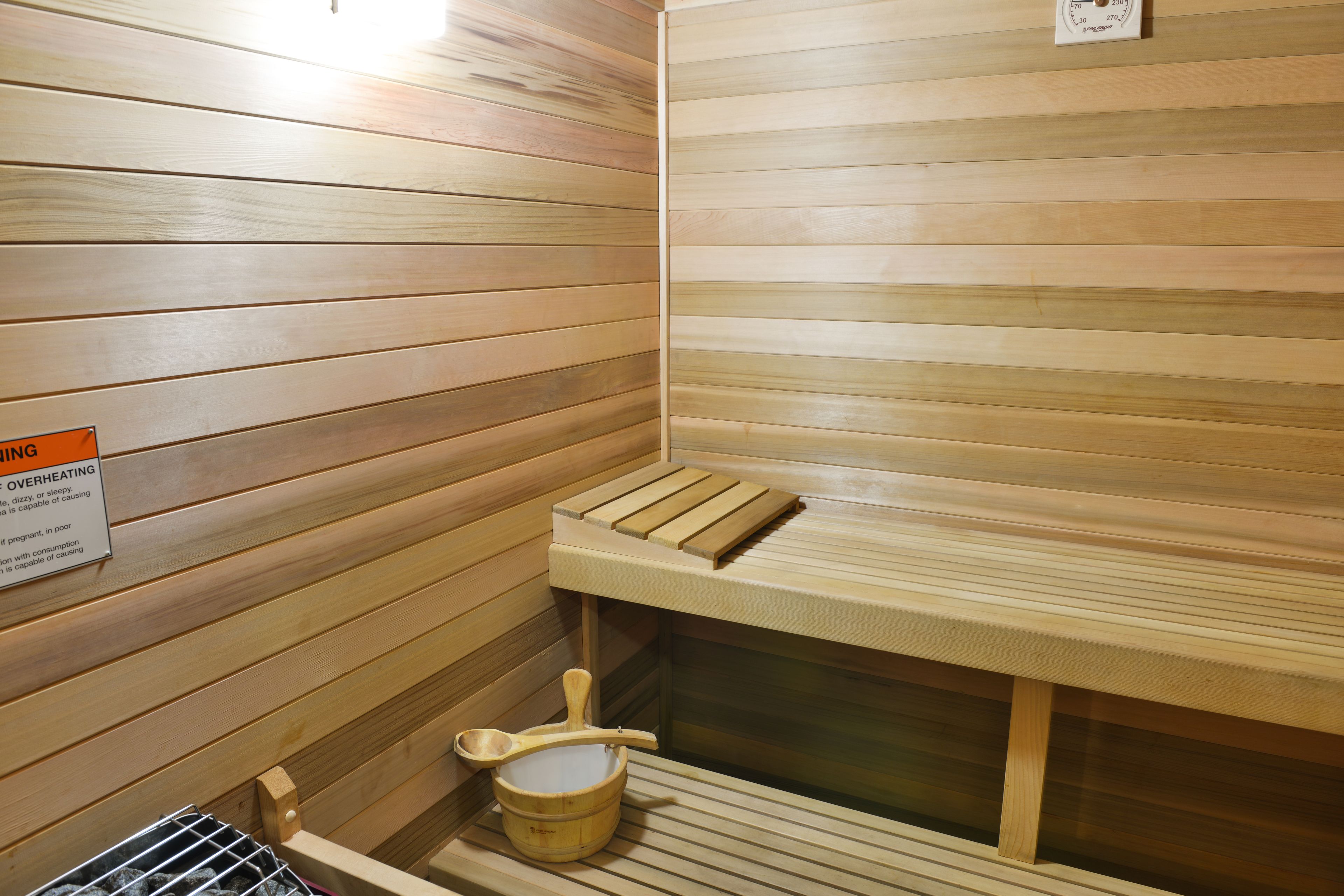 Un sauna con bancos de madera y un balde de madera.