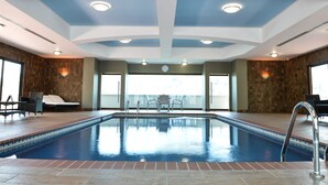 Piscina con diseño en el techo, un reloj y vistas al exterior.