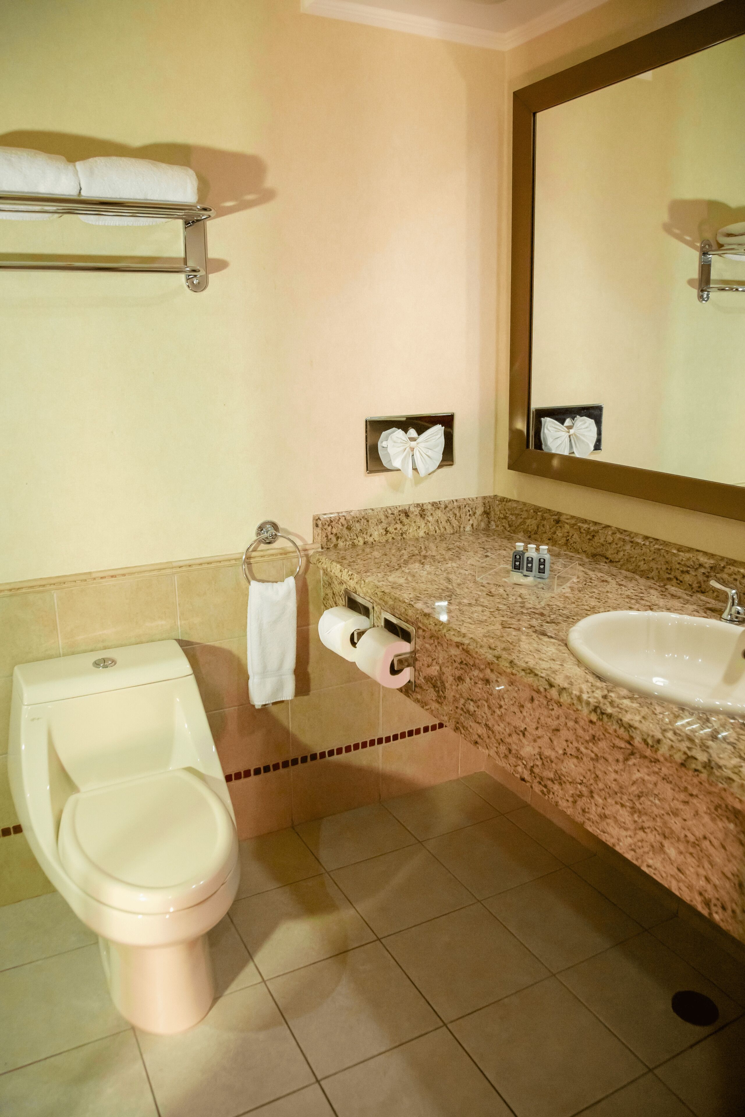 A bathroom with a toilet, bidet, sink, and towel rack.