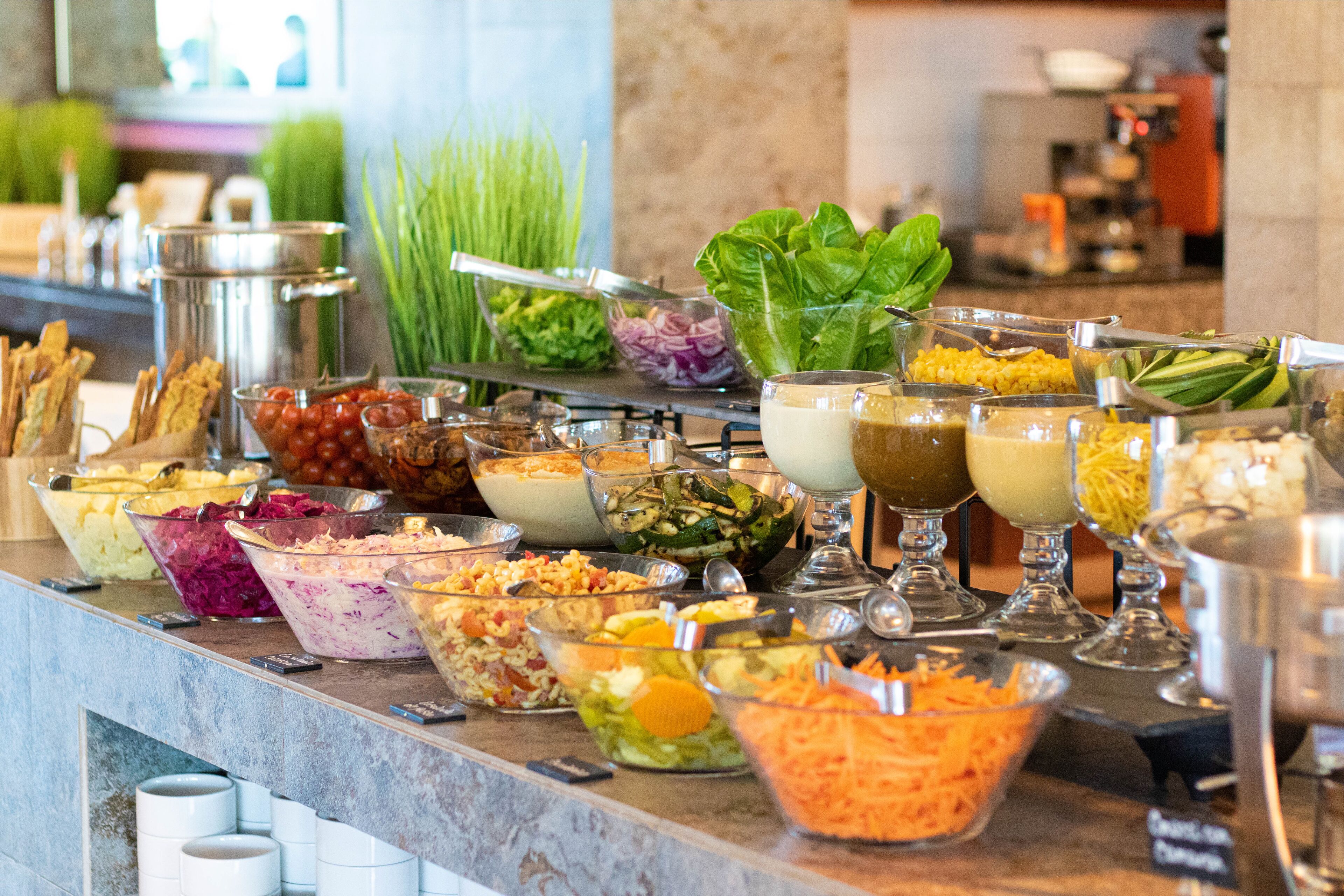 A buffet with various food options including salads, grains, and vegetables.