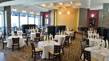 A restaurant with multiple tables set for dining, featuring white tablecloths and chairs.