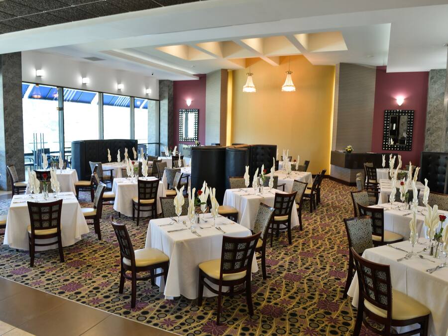 A restaurant with multiple tables set for dining, featuring white tablecloths and chairs.