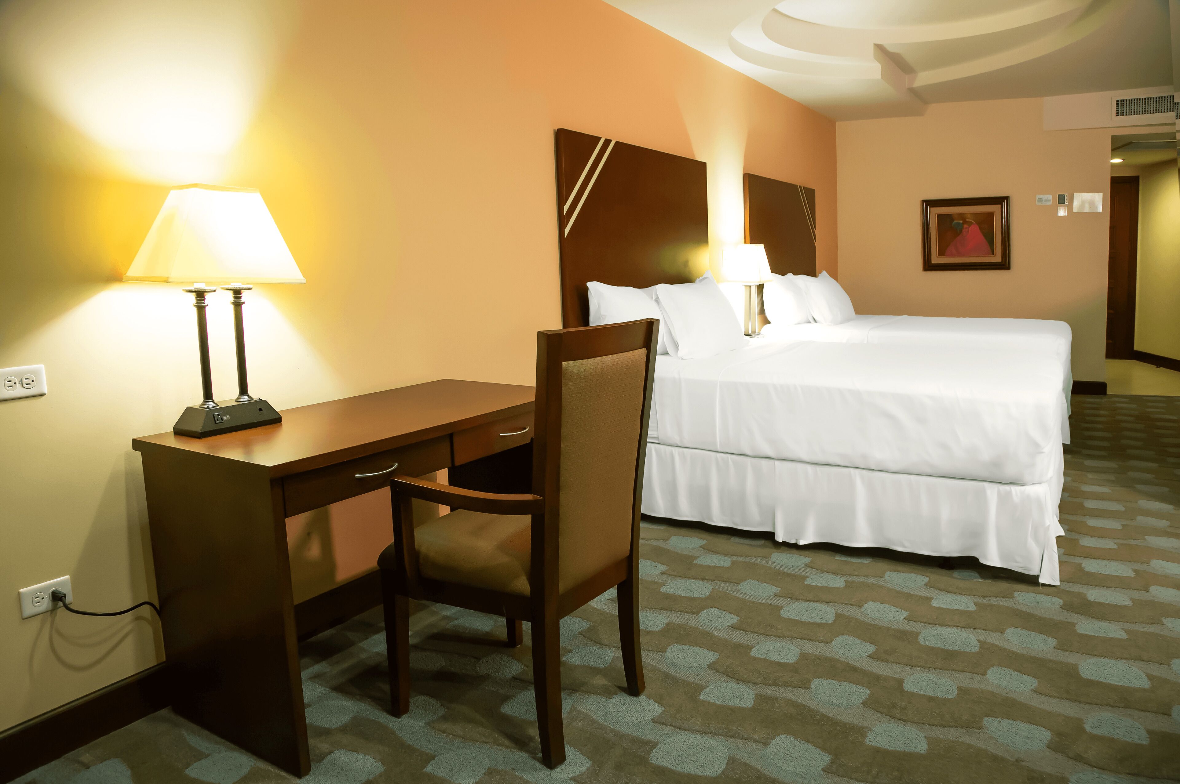 Ein Hotelzimmer mit Bett, Schreibtisch, Stuhl und Lampe.
