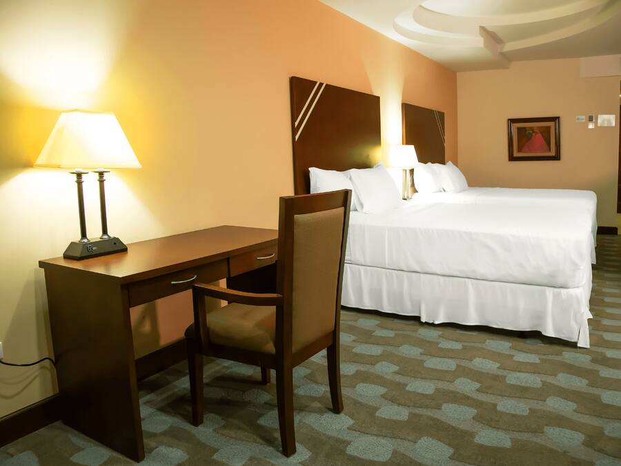 Ein Hotelzimmer mit Bett, Schreibtisch, Stuhl und Lampe.